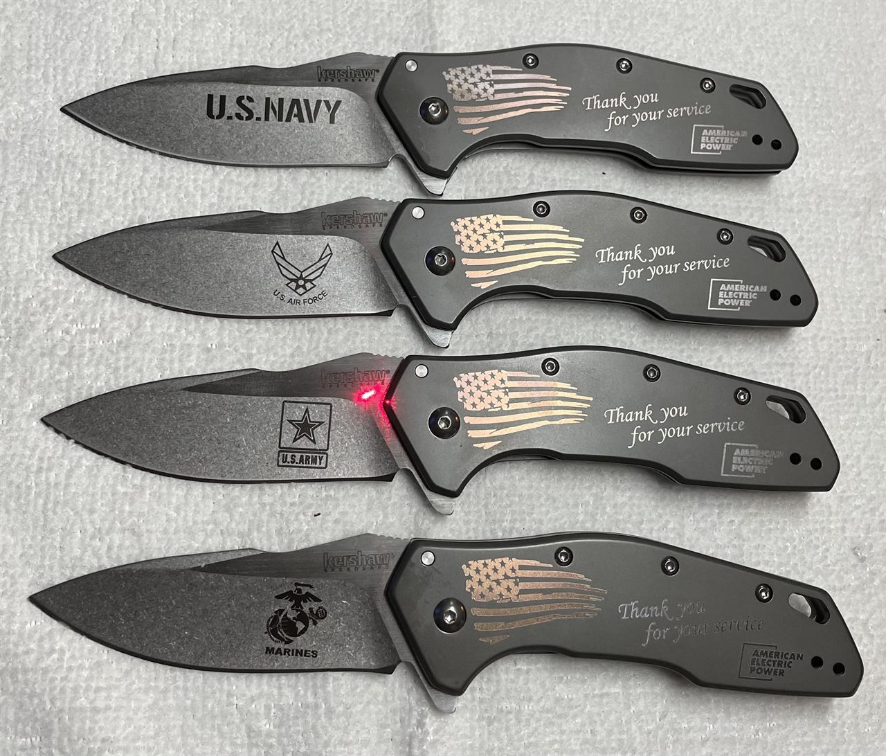 Four folding knives engraved with military branch crests and Thank you for your service